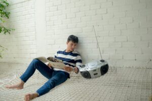 boy sitting near radio holding white catalog