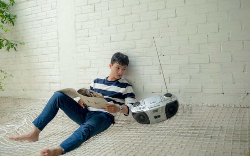 boy sitting near radio holding white catalog